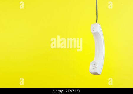 Combiné téléphonique blanc avec ombre douce sur jaune Banque D'Images