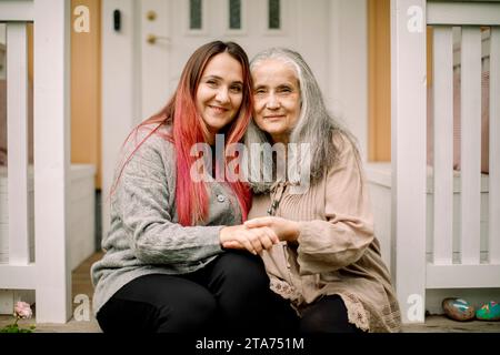 Portrait de femme aînée souriante assise avec sa fille au porche Banque D'Images