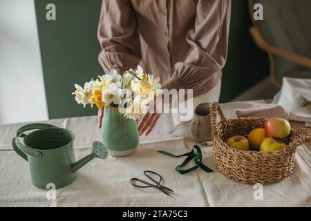 Gros plan d'une femme arrangeant un bouquet de jonquilles dans un vase Banque D'Images
