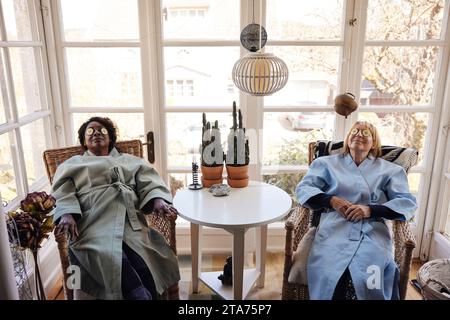 Amis féminins multiraciaux se relaxant avec des tranches de concombre sur les yeux à la maison Banque D'Images