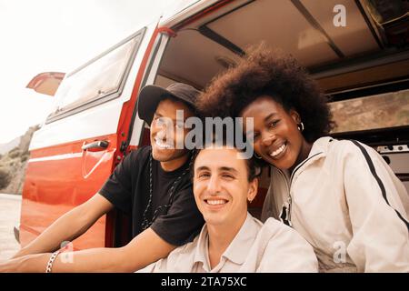 Portrait d'amis souriants multiraciaux masculins et féminins assis dans la camionnette Banque D'Images