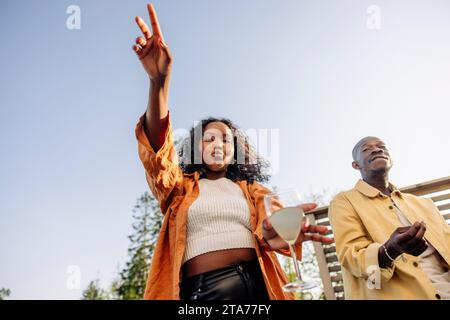 Vue à angle bas de la femme plissonnant et dansant avec un ami masculin à la fête Banque D'Images