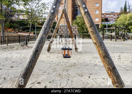 Une aire de jeux urbaine avec balançoires et toboggans sur un sol sablonneux Banque D'Images