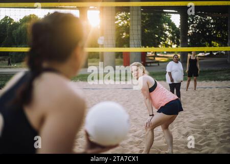 Femme mature regardant un ami tenant le volley-ball Banque D'Images