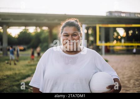 Portrait de femme surdimensionnée souriante tenant le volley-ball Banque D'Images