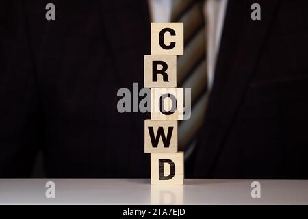 le mot crowd fait de lettres en bois se trouve sur une table jaune. Banque D'Images