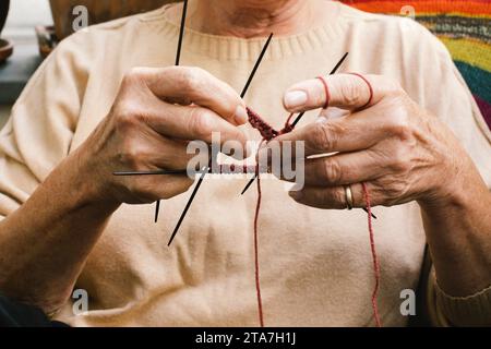 Section médiane d'une femme âgée tricotant assise à la maison Banque D'Images