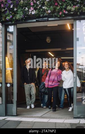 Souriant des amis adolescents masculins et féminins quittant le magasin Banque D'Images