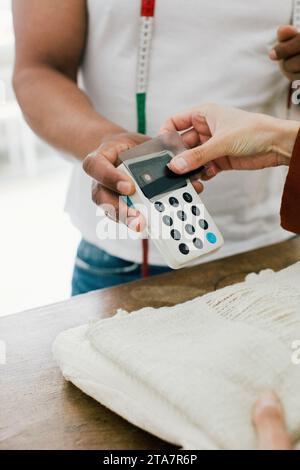 Main du client payant par carte de crédit au magasin Banque D'Images