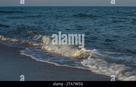 Une grande et forte onde de tempête de couleur turquoise avec des éclaboussures de mousse blanche coule et se brise sur le rivage. Banque D'Images
