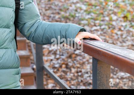 femme se tenant à la balustrade en bois descendant les escaliers. main tenant la main courante. Banque D'Images