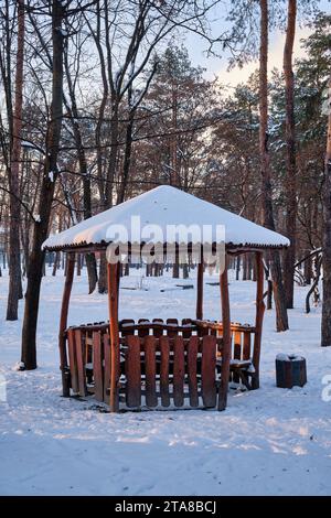 vieux belvédère en bois dans un parc d'hiver par une journée ensoleillée. belvédère en bois dans le parc. belvédère en bois recouvert de neige dans le parc. Banque D'Images