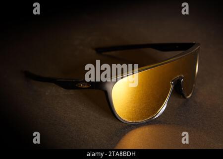 Une photo studio fantastique d'une paire de lunettes de soleil Oakley sportives avec lentille dorée, sur un fond noir foncé Banque D'Images