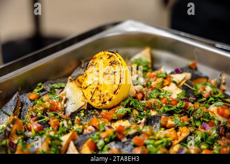 Poisson grillé avec citron, persil et oignon sur un plateau en métal. Restauration buffet à l'intérieur dans un restaurant de luxe avec des fruits et légumes colorés au saumon Banque D'Images