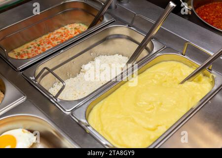 Fast food bistro, nourriture dans des plateaux en métal, salade de côtelettes garniture sur la fenêtre du café, patches avec nourriture sur le comptoir de bistro, viande et garniture dans des patches. Banque D'Images