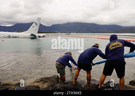 Kaneohe Bay, États-Unis. 26 novembre 2023. Des plongeurs de l'US Navy récupèrent un tuyau de carburant après des opérations réussies de ravitaillement sur un avion P-8a Poseidon de l'US Navy abattu qui a dépassé la piste dans l'eau à la base aérienne du corps des Marines Kaneohe Bay, le 26 novembre 2023 dans la baie de Kaneohe, Hawaii. Crédit : Sgt. Brandon Aultman/É.-U. Marine corps/Alamy Live News Banque D'Images