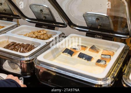 Rangée de plats buffet ouverts dans la salle de banquet. Plat à frotter prêt pour le service en acier inoxydable au buffet. Banque D'Images