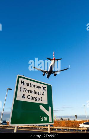 Avion à réaction BA Airliner en finale pour atterrir à l'aéroport de Londres Heathrow, Royaume-Uni, survolant le panneau de signalisation routière avec les indications pour Heathrow terminal 4 & Cargo Banque D'Images