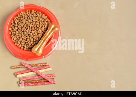 Bol avec de la nourriture sèche pour chien et des friandises sur fond de couleur Banque D'Images