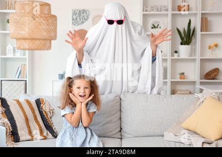 Père en costume fantôme effrayant sa petite fille à la maison Banque D'Images
