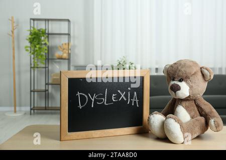 Ours en peluche et petit tableau noir avec mot Dyslexia sur une table en bois à l'intérieur Banque D'Images