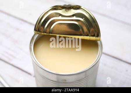 Savoureux lait condensé dans une boîte de conserve sur une table en bois blanc, gros plan Banque D'Images