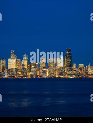 Seattle - 20 novembre 2023 ; les gratte-ciel urbains de Seattle s'illuminent à l'heure bleue derrière Elliott Bay alors que le paysage urbain brille sur l'eau bleue et le ciel Banque D'Images