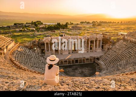 Hiérapolis ancienne ville Pamukkale Turquie, une jeune femme avec un chapeau regardant le coucher du soleil par les ruines patrimoine de l'UNESCO. Femmes asiatiques regardant le coucher du soleil à l'ancien amphithéâtre en Turquie pendant les vacances Banque D'Images