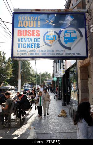 Un panneau de billetterie de bus sur le trottoir de l'Avenida del Libertador, la rue principale d'El Calafate avec des piétons et un café-terrasse. Santa Cruz.Argentine Banque D'Images