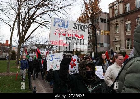 University Park, États-Unis. 29 novembre 2023. Des manifestants brandissent des pancartes lors d'un rassemblement pro-palestinien à State College, Pennsylvanie, le 29 novembre 2023. Les manifestants se sont rassemblés à Allen Street de Penn State, puis ont marché vers Old main pour présenter leurs revendications, qui incluent le désinvestissement des fabricants d'armes et une condamnation de la « guerre de génocide israélienne en cours contre la Palestine », à l'administration de l'université. (Photo de Paul Weaver/Sipa USA) crédit : SIPA USA/Alamy Live News Banque D'Images