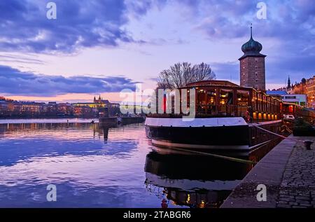 Le ciel violet au-dessus du château d'eau médiéval de Sitkov derrière le bateau-restaurant sur la rivière Vltava, Prague, Tchéquie Banque D'Images