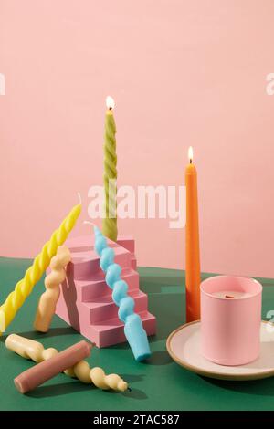 Des bougies torsadées de différentes couleurs sont placées autour du podium en terrasse rose, à côté d'un pot de bougies parfumées placé sur une plaque en céramique. Espace pour Banque D'Images