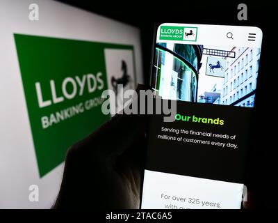 Personne détenant un smartphone avec la page Web de la société financière britannique Lloyds Banking Group plc devant le logo. Concentrez-vous sur le centre de l'écran du téléphone. Banque D'Images