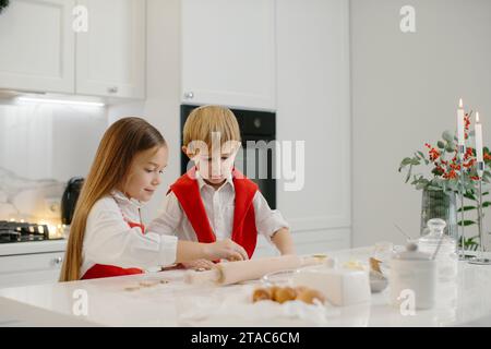 Une fille et son jeune frère font des biscuits de Noël dans la cuisine. Banque D'Images