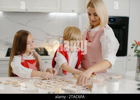 Les enfants et leur mère découpaient des biscuits de la pâte. Une petite fille et un garçon font des biscuits de Noël dans la cuisine. Banque D'Images