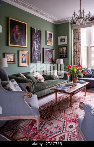 Fauteuil antique et canapé avec des œuvres d'art encadrées dans le salon de la fin du 19e siècle West London maison. Banque D'Images