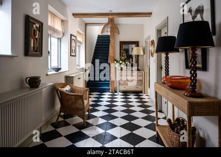 Plancher peint en noir et blanc avec escalier bleu de la Haye dans le hall d'entrée de la maison de style Arts and Crafts des années 1930. Hove, East Sussex, Royaume-Uni. Banque D'Images