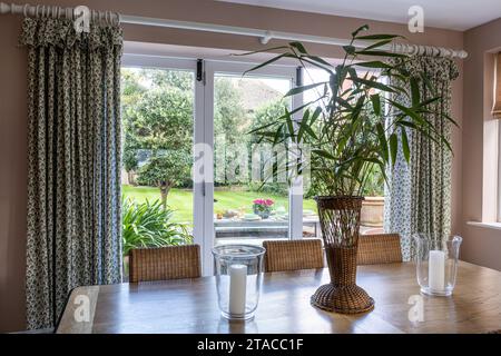 Bambou dans vase en osier sur la table avec vue sur le jardin. Maison de style art et artisanat des années 1930. Hove, East Sussex, Royaume-Uni. Banque D'Images