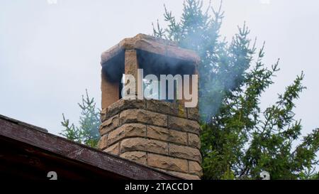 fumée de la cheminée. Un immeuble résidentiel dans la banlieue par une journée nuageuse dans un hiver froid pollue l'air avec une épaisse fumée sombre. Du smog sort Banque D'Images