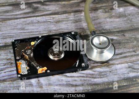 Un stéthoscope médical sur un ordinateur portable mémoire de stockage de disque dur de 2,5 pouces, réparation de la partie cassée de l'ordinateur, un disque dur ouvert avec des plateaux, broche, actu Banque D'Images