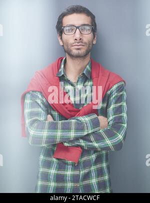 Portrait de bel homme confiant, posant devant le fond gris. Banque D'Images