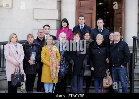 (De gauche à droite) Lynda McManus, Martina Dillon, Michael McManus, Harry Robinson, Donna McManus, Mairead Kelly, Grainne Teggart, directrice adjointe d'Amnesty International Royaume-Uni pour l'Irlande du Nord, Brigid Hughes, Darragh Mackin, Deirdre Hughes, Irene McEvoy, avocate de Phoenix Gavin Booth, Sinead Marmion et John McEvoy, à la haute Cour de Belfast, suite aux derniers arguments dans la contestation judiciaire de la loi sur l'héritage du gouvernement. Date de la photo : jeudi 30 novembre 2023. Banque D'Images