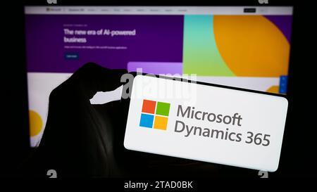 Personne tenant le téléphone portable avec le logo du produit logiciel de comptabilité Microsoft Dynamics 365 devant la page Web de l'entreprise. Concentrez-vous sur l'affichage du téléphone. Banque D'Images