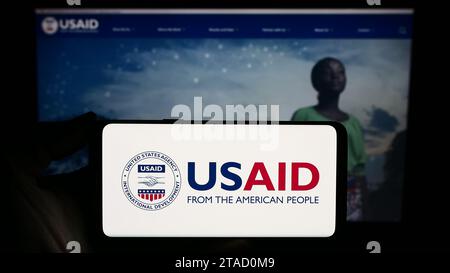 Personne tenant un smartphone avec sceau de l'Agence des États-Unis pour le développement international (USAID) devant le site Web. Concentrez-vous sur l'affichage du téléphone. Banque D'Images