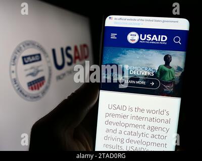 Personne tenant un téléphone portable avec une page Web de l'Agence des États-Unis pour le développement international (USAID) avec logo. Concentrez-vous sur le centre de l'écran du téléphone. Banque D'Images
