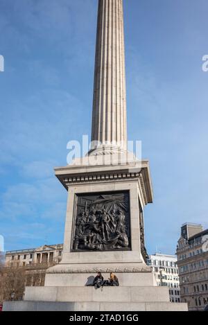 Deux jeunes femmes assises sur les marches au pied de la colonne Nelson, Trafalgar Square, Londres Banque D'Images