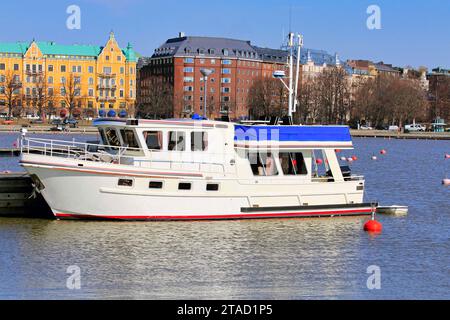 Bateau de plaisance blanc amarré à la marina par une journée ensoleillée du printemps. En arrière-plan, front de mer Merisatama et Compass Square, Helsinki, Finlande. Banque D'Images