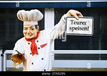 Figure brisée d'Un chef en face d'Un restaurant avec signe et inscription manger plus cher!, dans la Gastronomie, la TVA sur la nourriture est de nouveau portée à 1 Banque D'Images