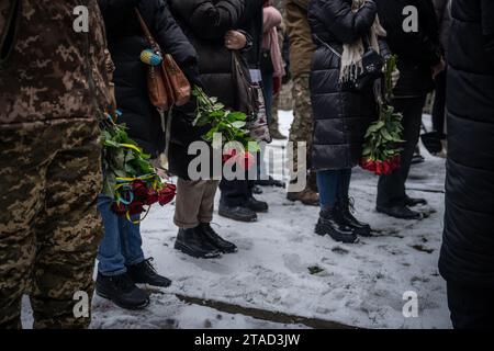 Kiev, Ukraine. 29 novembre 2023. Les personnes en deuil tiennent des fleurs et se tiennent debout dans la neige lors des funérailles du soldat ukrainien Serhiy Pavlichenko, mort au combat dans la région de Zaporizhjhia lors de l'invasion continue de l'Ukraine par la Russie, dans un cimetière militaire de Kiev. Depuis que la Russie a commencé son invasion à grande échelle de l'Ukraine le 24 février 2022, des dizaines de milliers de militaires ukrainiens et russes ont été tués. (Photo Laurel Chor/SOPA Images/Sipa USA) crédit : SIPA USA/Alamy Live News Banque D'Images