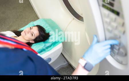 Un technologue en acquisition CT qui regarde le patient dans le scanner de tomodensitométrie pendant la préparation de la procédure. Femme entrant dans le scanner CT. Banque D'Images